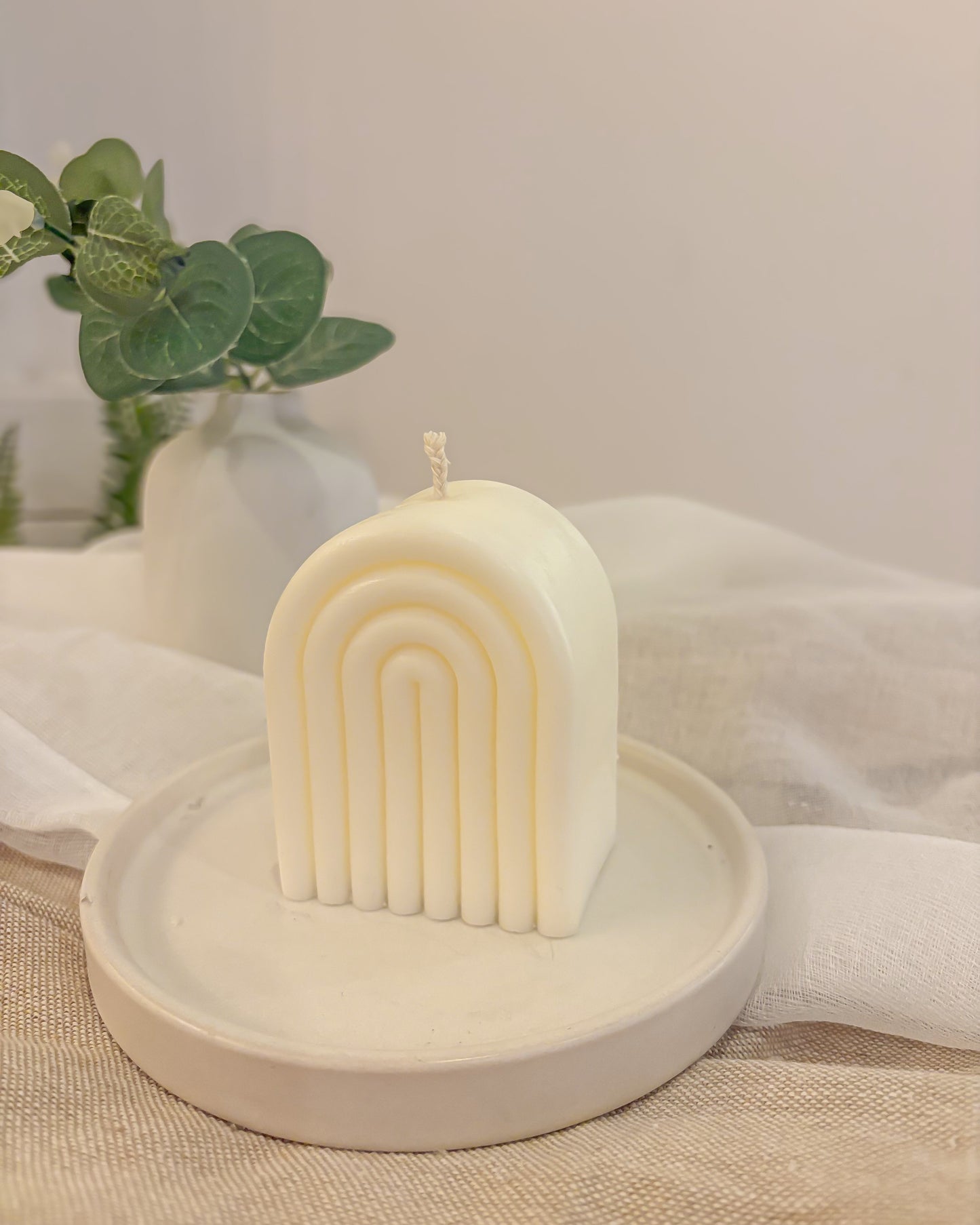 Arch-shaped candle on a white plate with a soft background