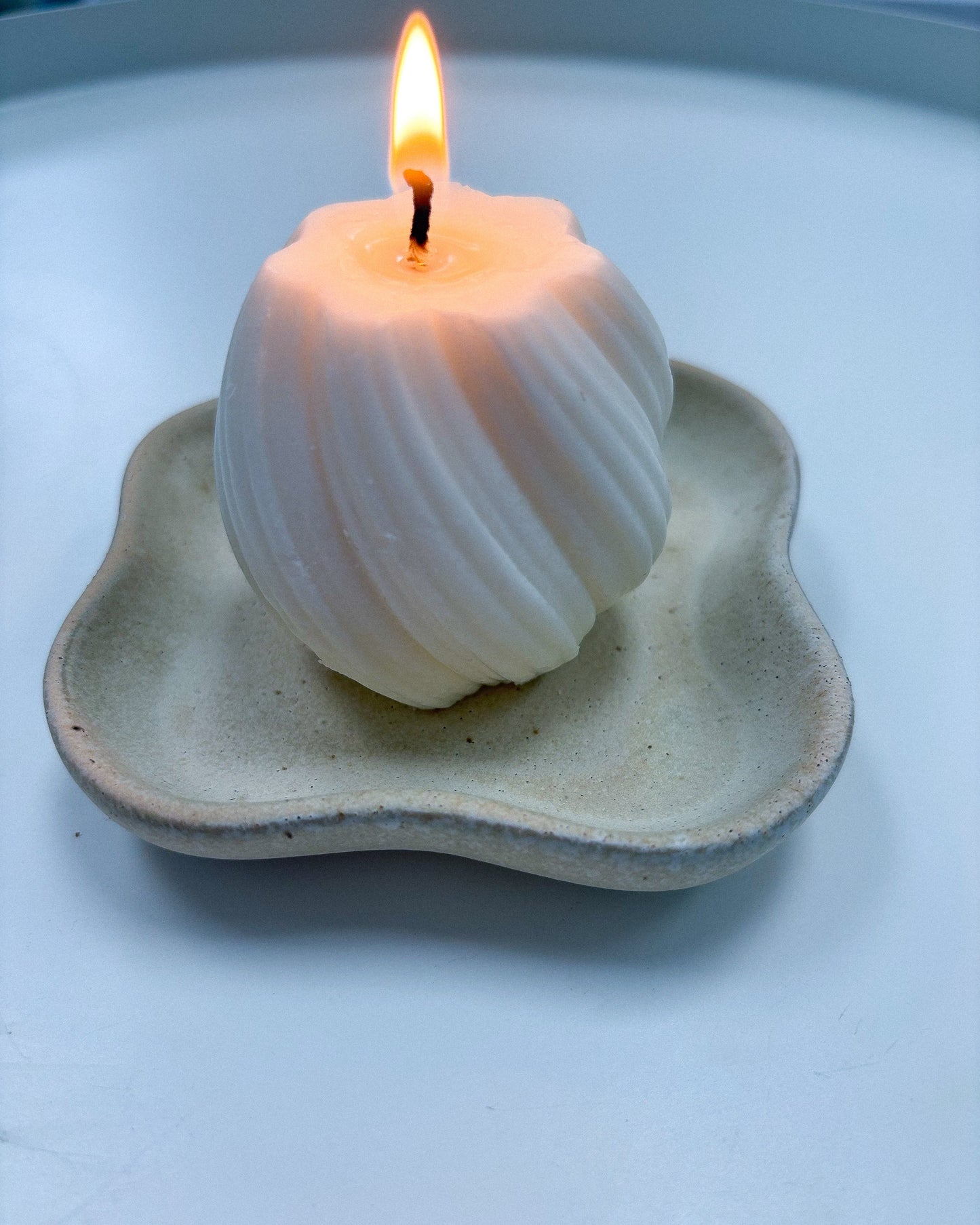 Candle in a shell holder on a white surface