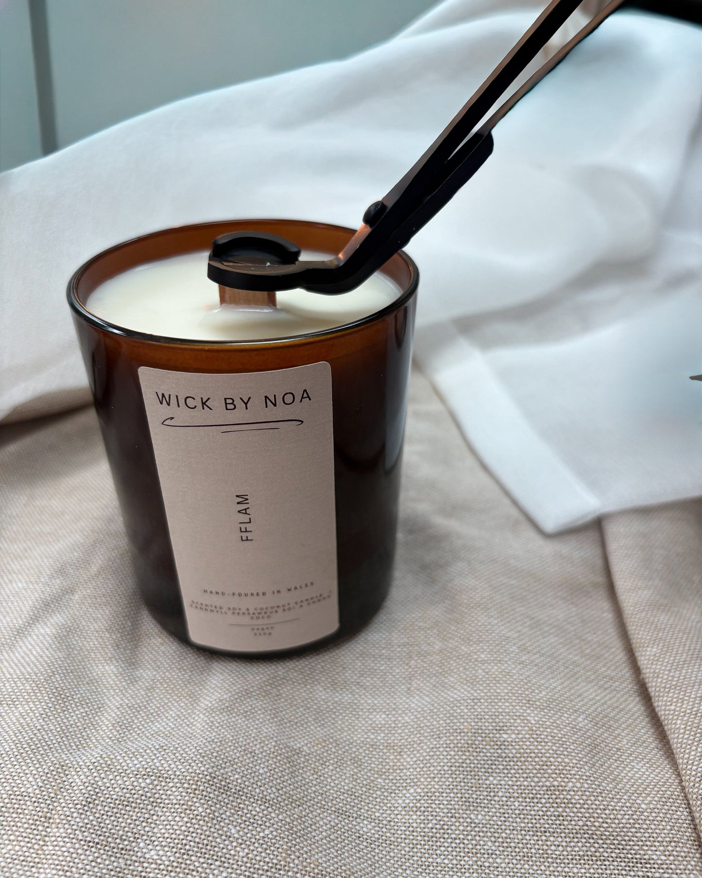 Candle with a label 'Wick by Noa' on a textured surface.