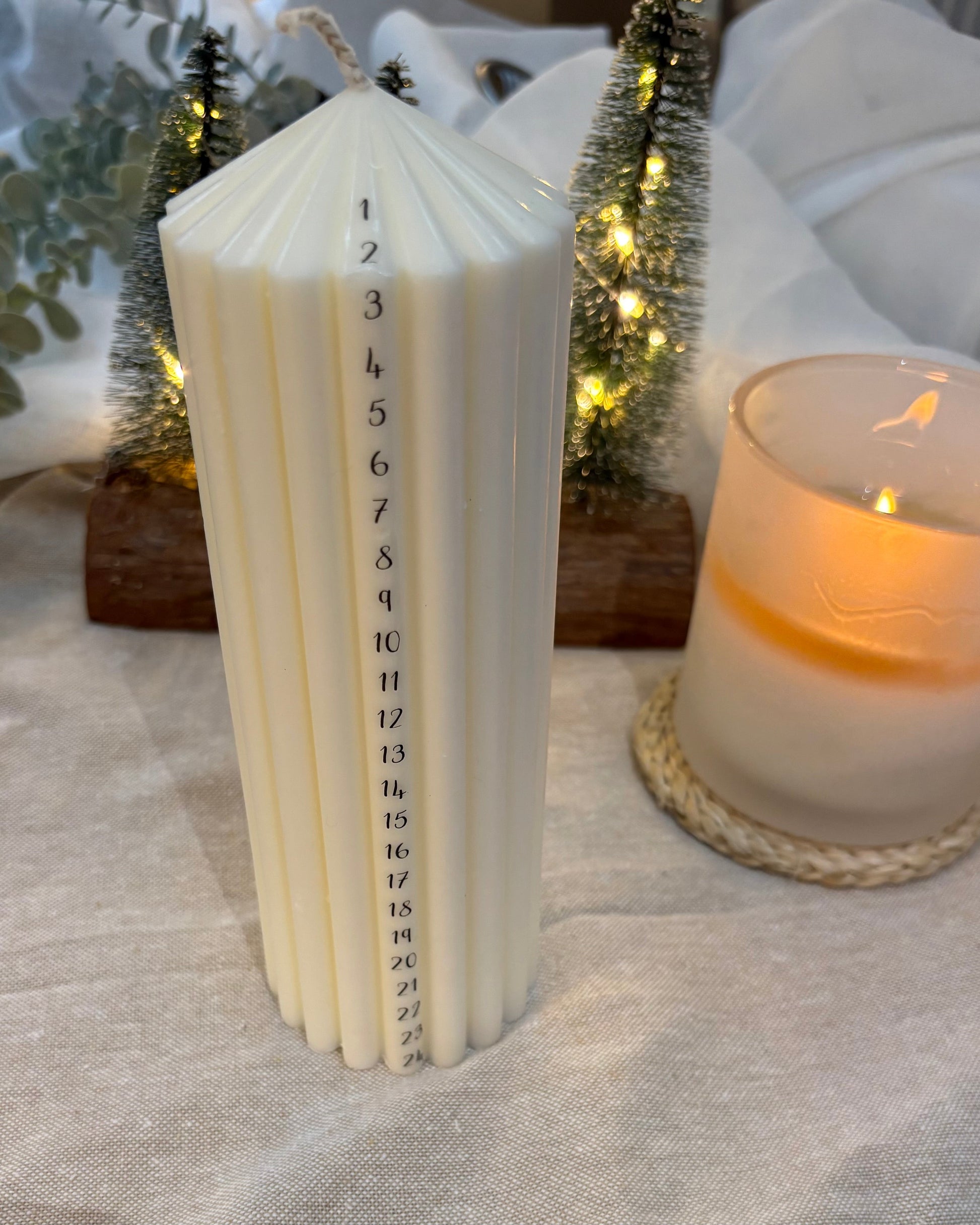 White candle with numbers on a textured surface with another candle in the background.